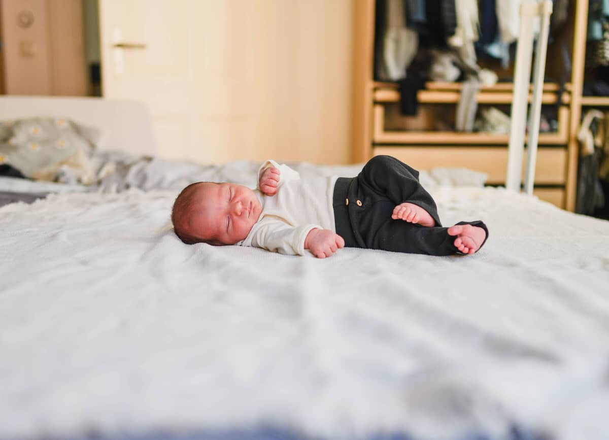 Neugeborenes Baby liegt auf dem Elternbett bei einer Newborn Homestory
