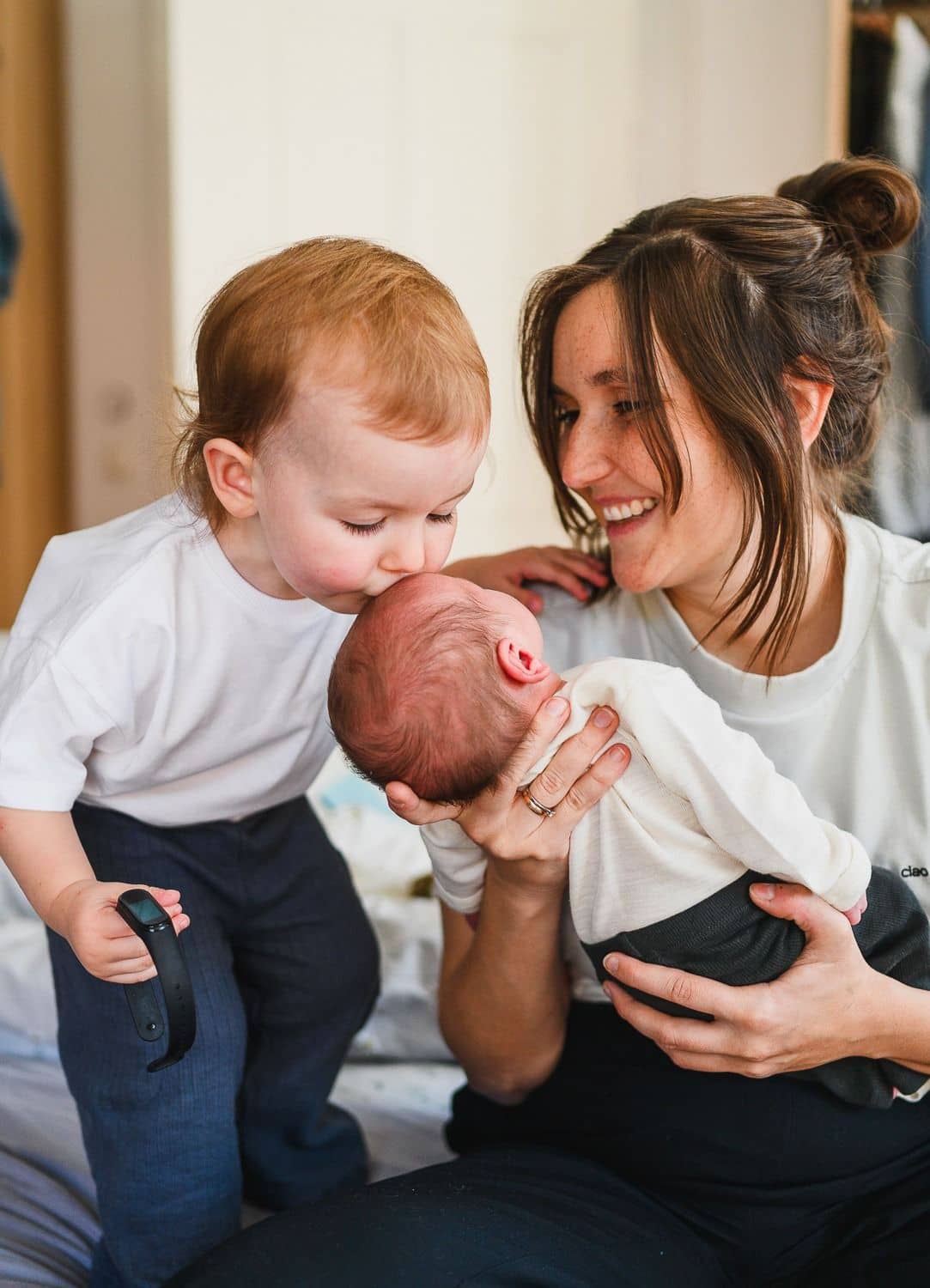 Mama mit Kleinkind und Neugeborenem beim Kuscheln