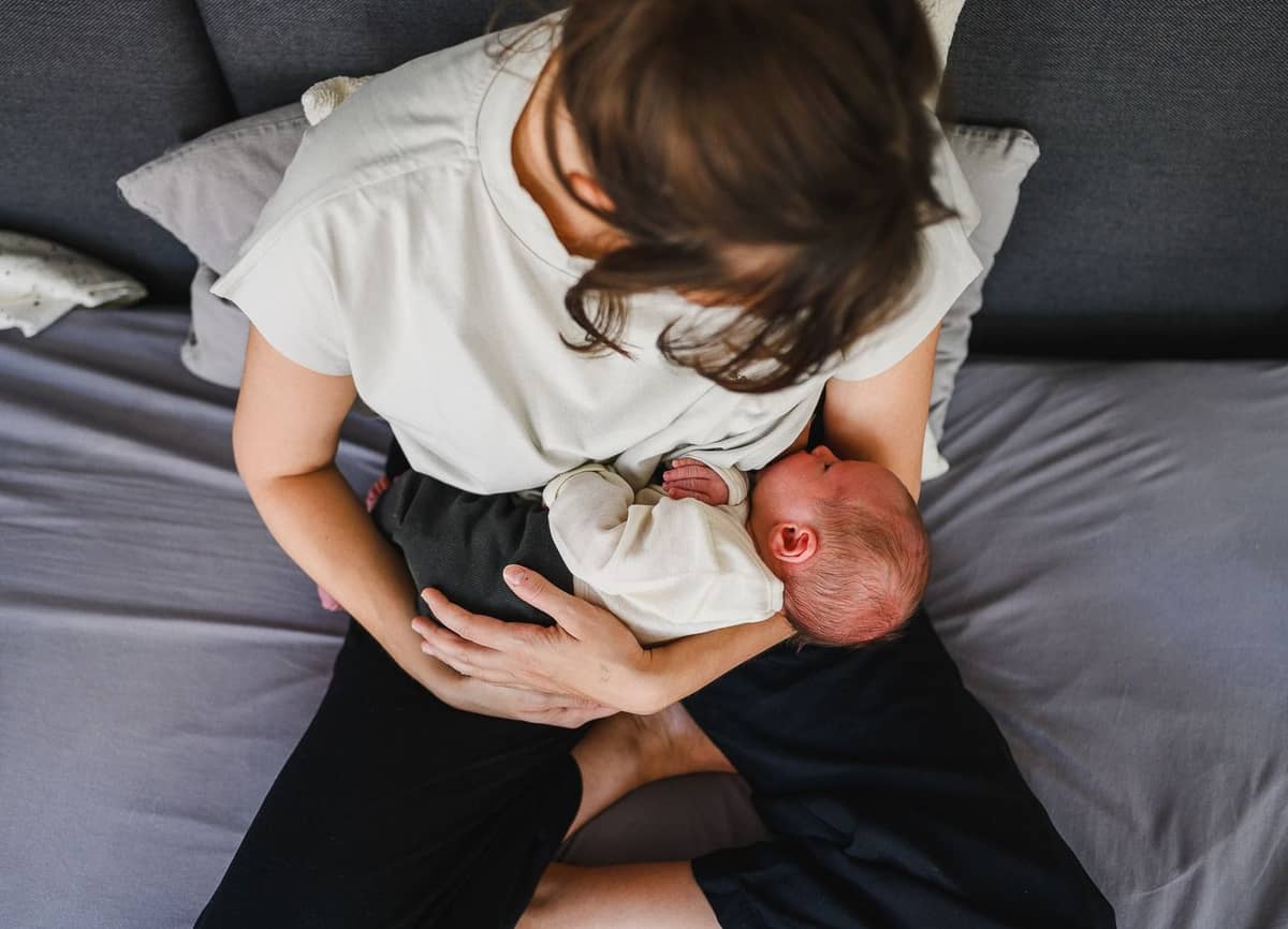 Mama hält ihr Baby auf dem Bett im Arm