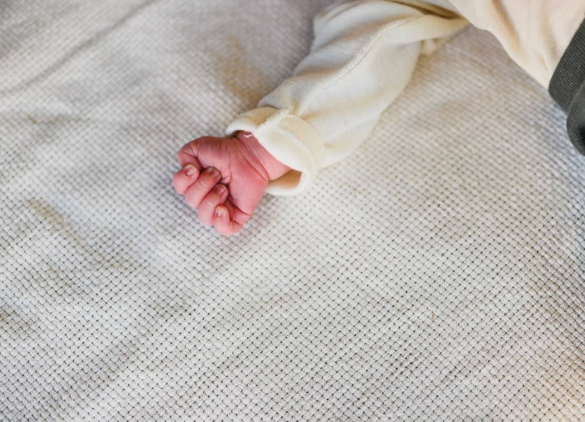 Kleine Babyhand auf einer hellen Decke