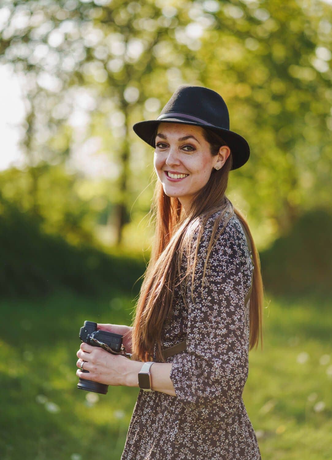 Fotografin Isabella Mues mit Hut und Kamera in der Natur