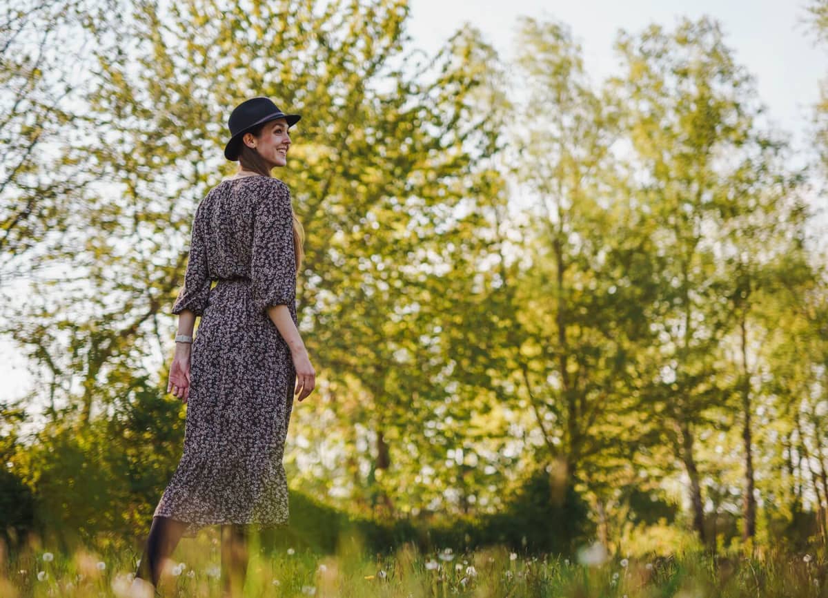 Isabella Mues mit Hut im Kleid auf einer sommerlichen Wiese