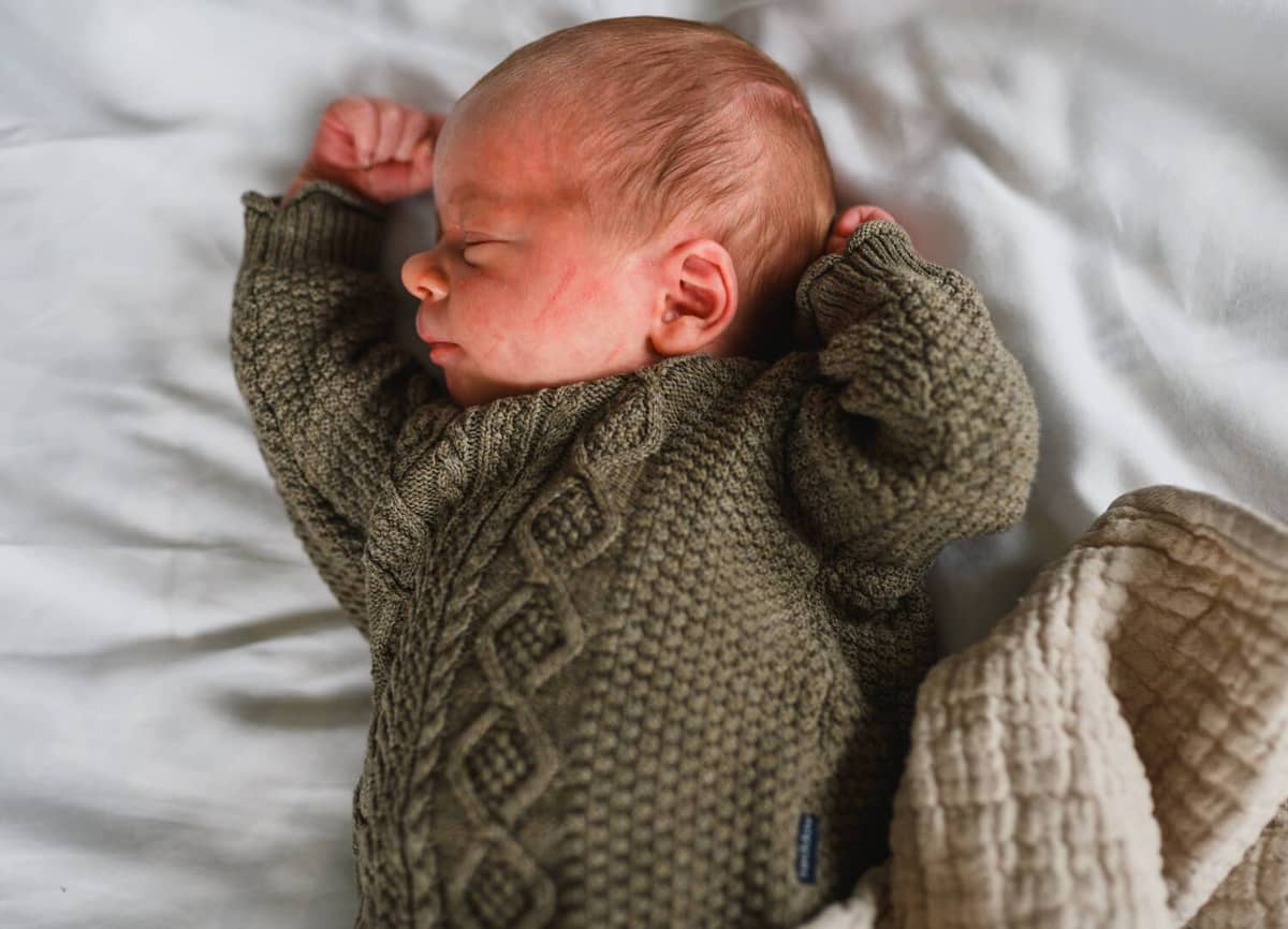 Schlafendes Neugeborenes im grünen Strickpullover
