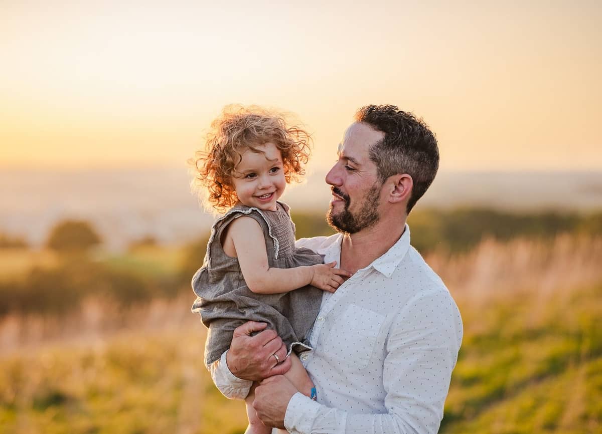 Papa hält seine Tochter auf dem Arm im Abendlicht