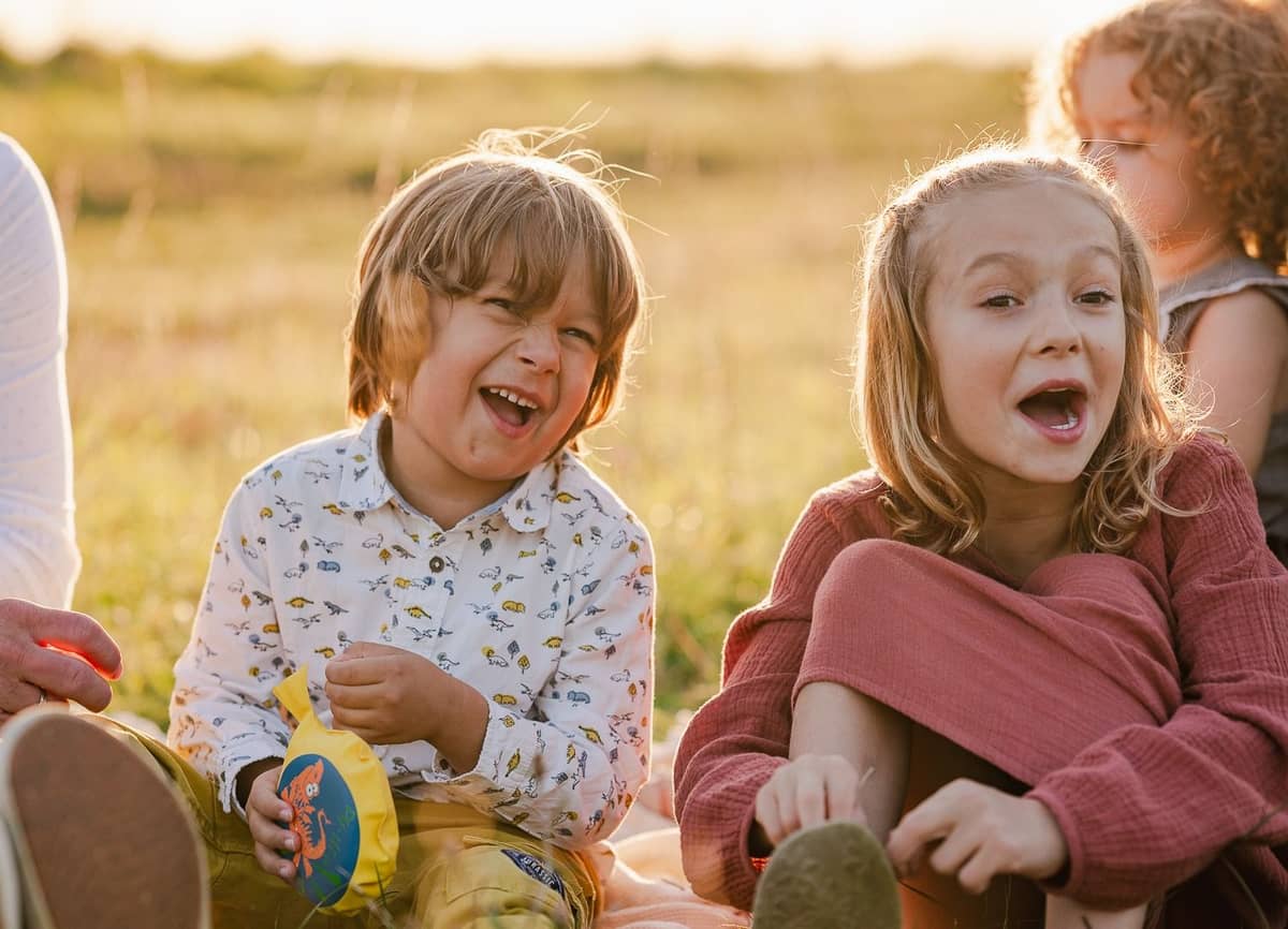 Zwei Kinder lachen ausgelassen im Gras