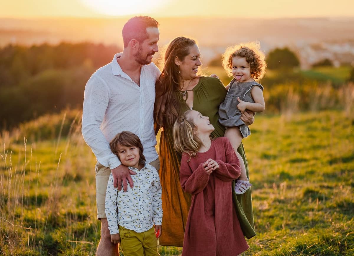 Familie mit drei Kindern kuschelt im goldenen Abendlicht